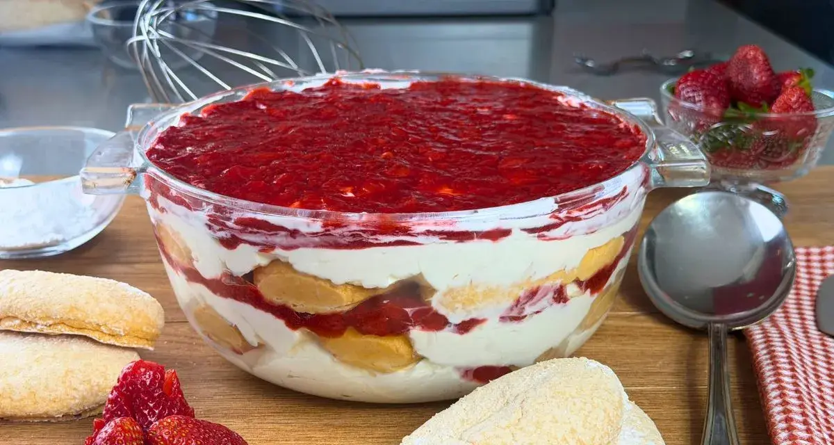 Un invitante tiramisù alle fragole in una ciotola di vetro, con savoiardi, crema e fragole fresche.