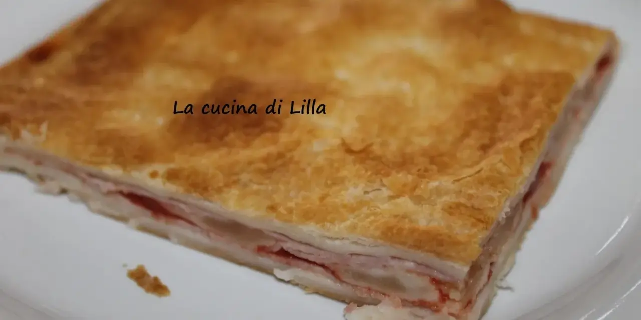 Una fetta di torta salata prosciutto e formaggio, con pasta sfoglia dorata e ripieno filante.