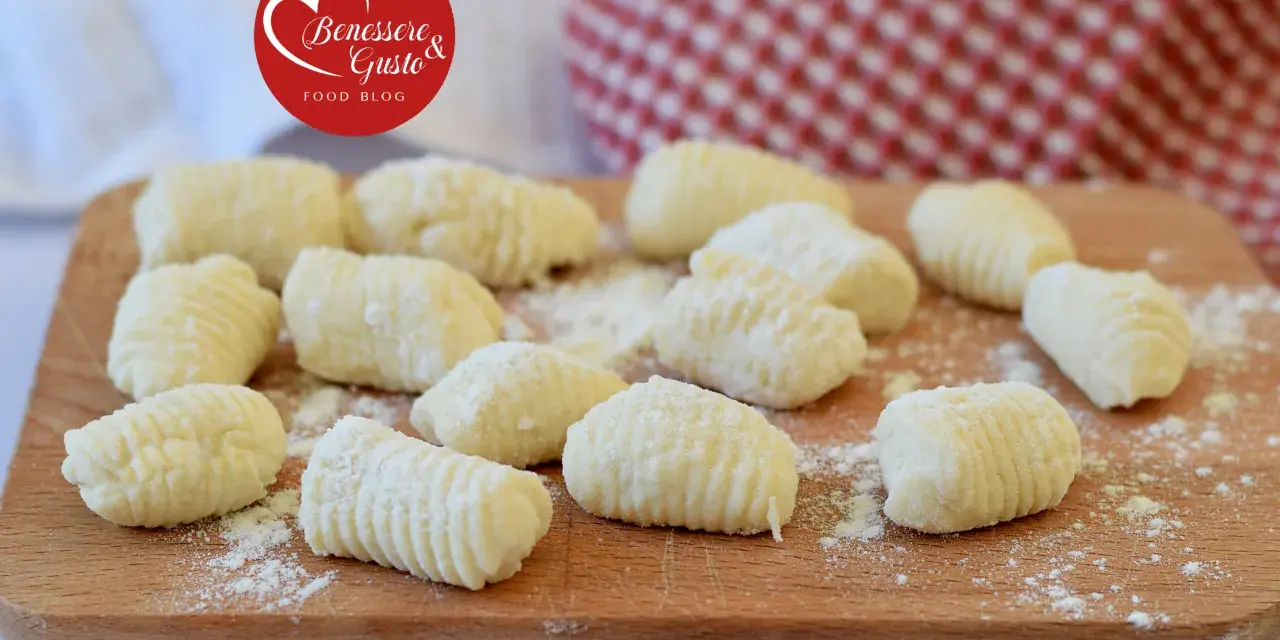 Gnocchi di ricotta freschi, pronti per essere cucinati, spolverati di farina su un tagliere di legno.