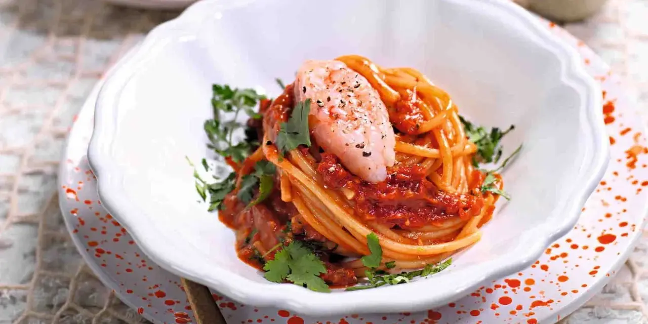 Spaghetti con gamberetti e pomodorini alla siciliana, un piatto colorato e saporito, guarnito con prezzemolo fresco.