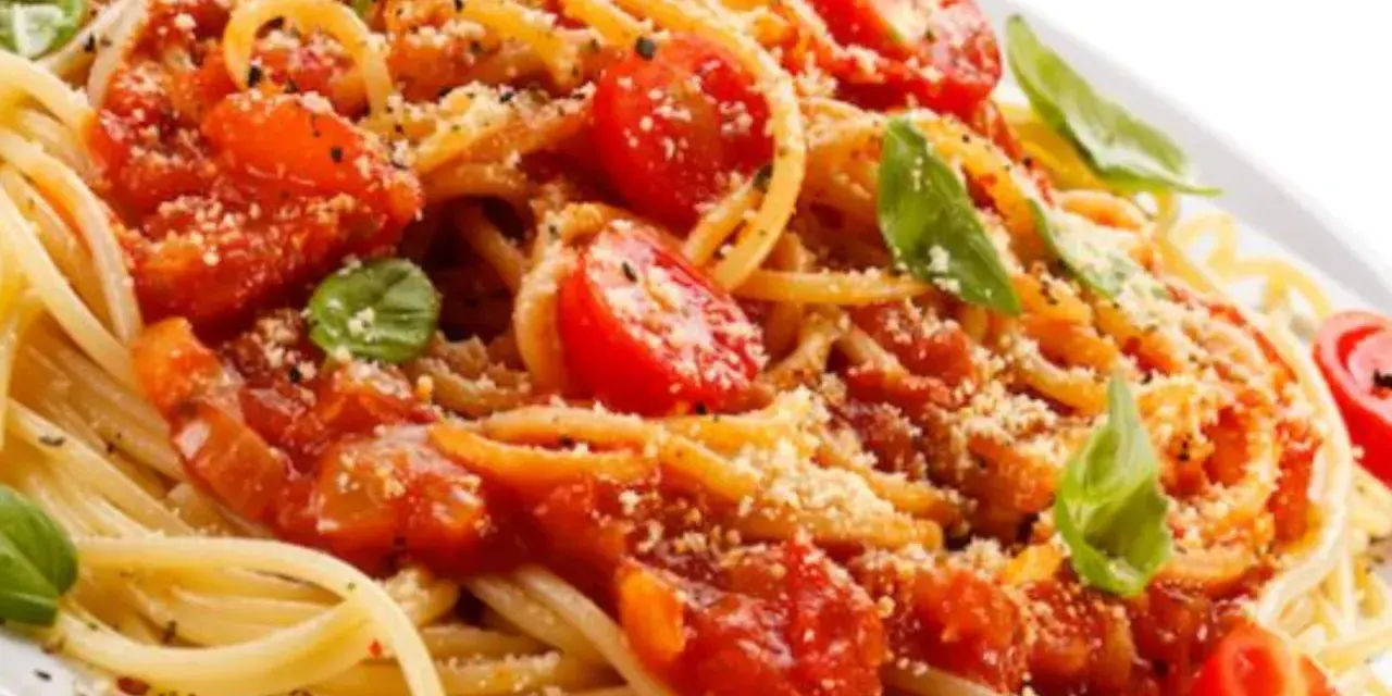 Un piatto di spaghetti alla carrettiera, conditi con pomodoro fresco, basilico e parmigiano grattugiato.