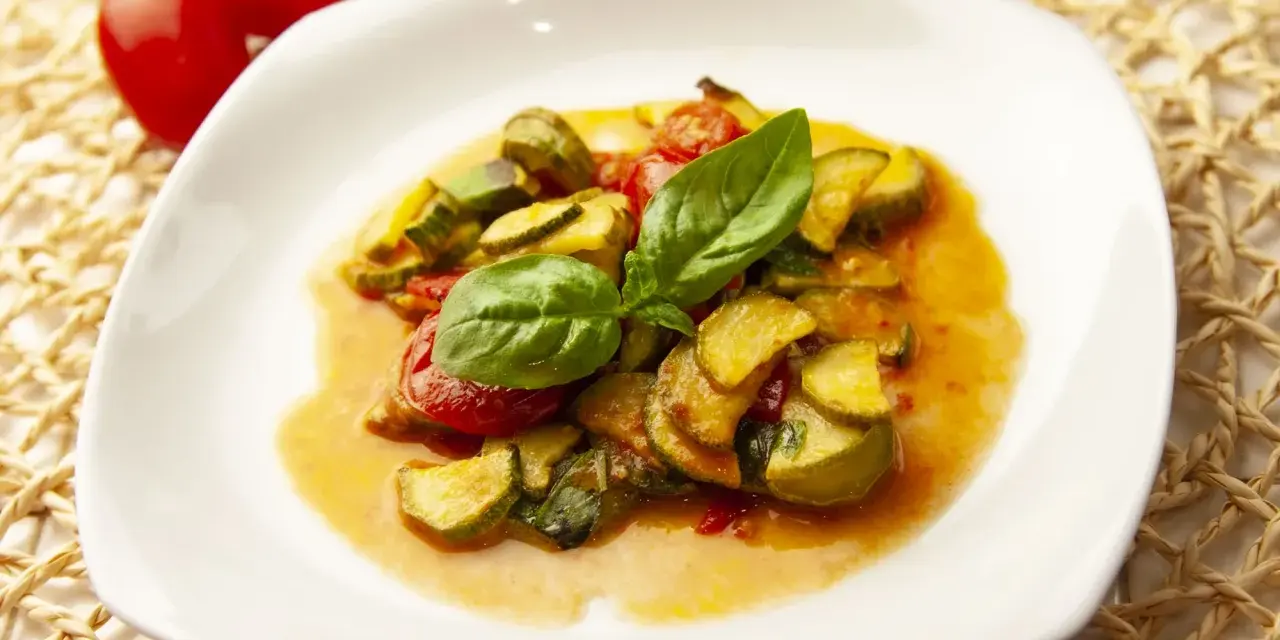 Zucchine in umido con pomodorini e basilico fresco, un piatto estivo profumato e saporito.