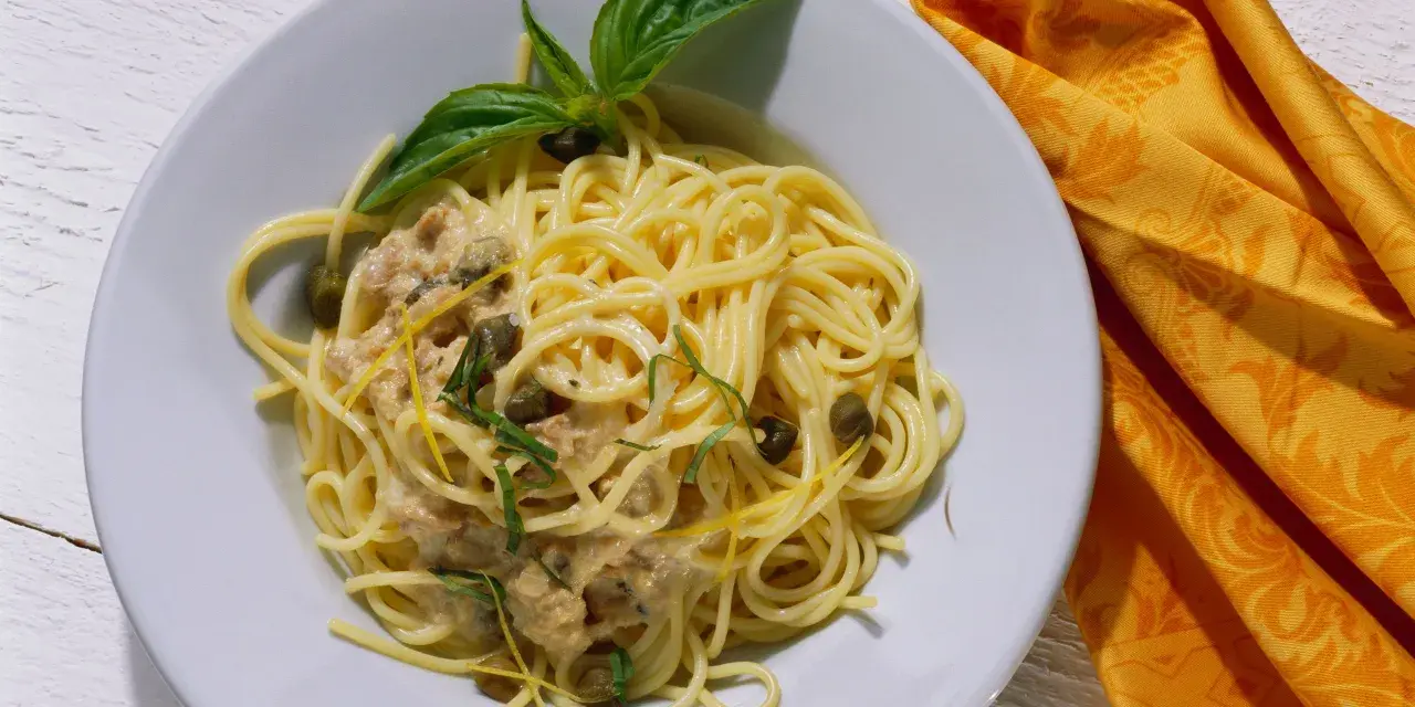Spaghetti al tonno con capperi, scorza di limone e basilico, un piatto gustoso e profumato.