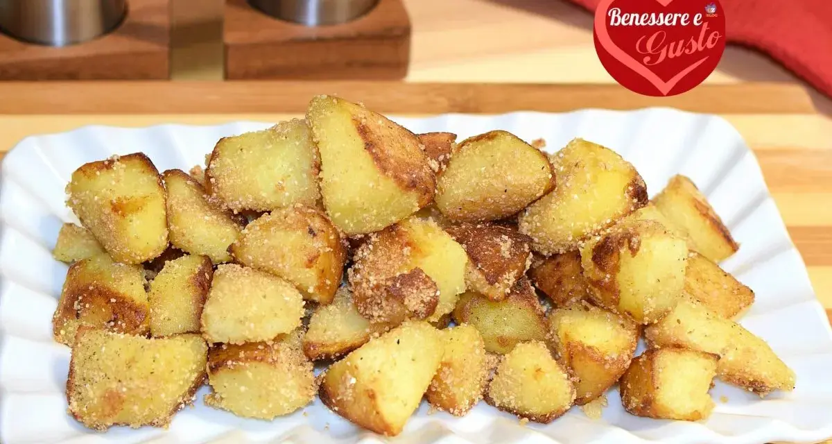 Patate sabbiose in padella, dorate e croccanti, servite su un piatto bianco. Un contorno irresistibile.