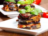Parmigiana di melanzane, un classico della cucina italiana, servita su un piatto bianco con basilico fresco.