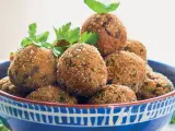 Polpette di melanzane dorate e croccanti, guarnite con prezzemolo fresco, in una ciotola blu decorata.