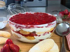 Un invitante tiramisù alle fragole in una ciotola di vetro, con savoiardi, crema e fragole fresche.