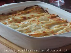 Lasagne con carciofi, besciamella e mozzarella appena sfornate, dorate e filanti in una teglia bianca.