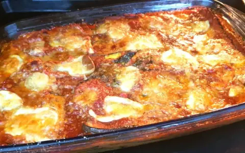 Parmigiana di melanzane non fritte appena sfornata, dorata e filante, pronta per essere gustata.
