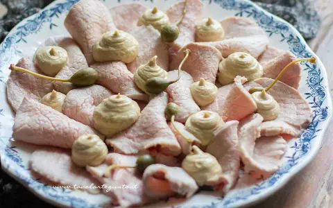 Piatto di vitello tonnato con salsa cremosa, capperi e guarnizioni.