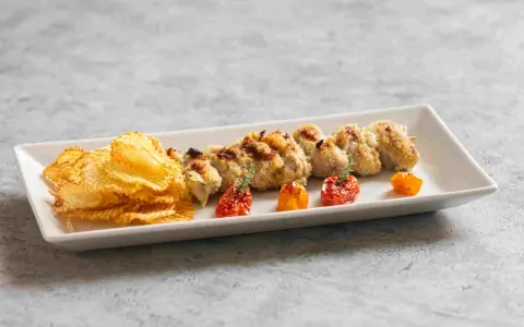 Involtini alla messinese su uno spiedino, accompagnati da patatine croccanti e pomodorini confit.