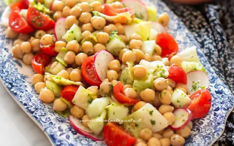 Deliziosa insalata di ceci fredda con pomodorini, cetrioli e ravanelli, condita con erbe fresche. Perfetta per un pasto leggero e gustoso.