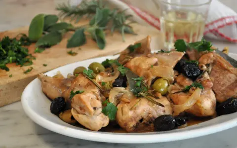 Piatto di coniglio alla cacciatora in bianco, con olive verdi e nere, cipolle e rosmarino.