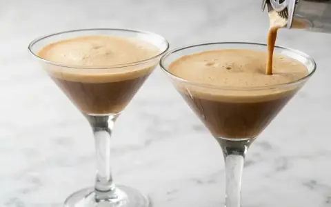 Due bicchieri di **caffè shakerato** con una schiuma densa e invitante. Uno viene riempito da uno shaker.