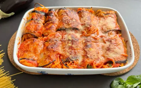 Involtini di melanzane con spaghetti al forno, ricoperti di sugo e formaggio filante, pronti per essere gustati.