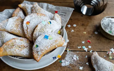 Cassatelle siciliane al forno, dolcetti dorati cosparsi di zucchero a velo e decorati con coriandoli colorati, pronti per essere gustati.