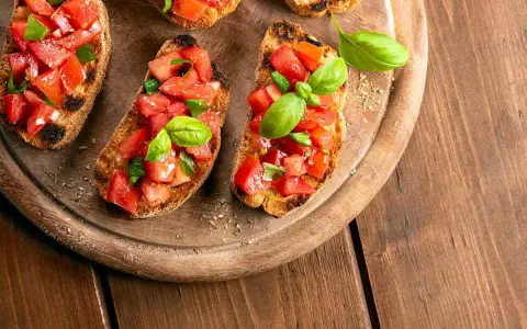 Bruschette veloci per aperitivo: fette di pane tostato con pomodoro fresco a cubetti e basilico, pronte per essere gustate.