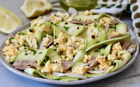 Deliziosa insalata di zucchine crude a nastro, condita con tonno, uova sode sbriciolate e prezzemolo fresco.