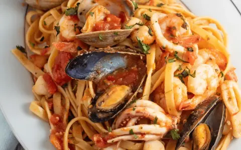 Un piatto invitante di scialatielli ai frutti di mare, con gamberi, cozze, vongole e calamari in un sugo rosso.