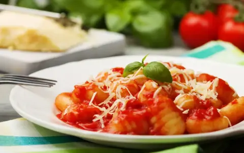 Gnocchi al pomodoro, un piatto semplice e gustoso, con basilico fresco e parmigiano grattugiato.
