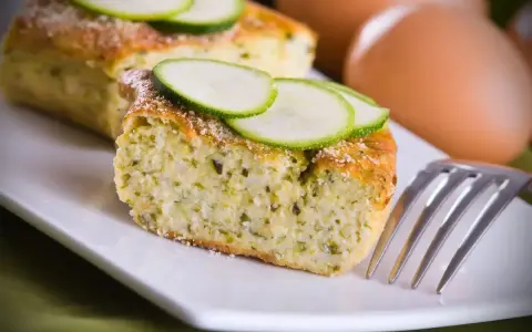 Delizioso sformato di zucchine, soffice e profumato, guarnito con fette di zucchina fresca. Perfetto per un pasto leggero.