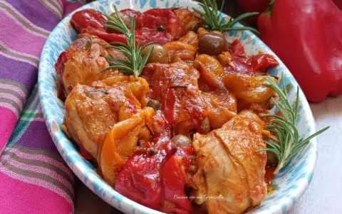 Un invitante pollo con peperoni alla siciliana, arricchito da olive e rosmarino, servito in un piatto decorato.