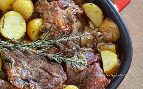 Agnello al forno con patate dorate e rosmarino, un piatto succulento pronto per essere gustato.