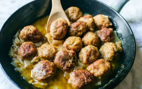 Polpette in bianco dorate e succulente, cotte in padella con cipolle dolci e un sughetto invitante. Un classico confortante.