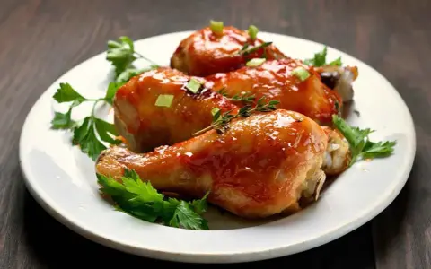 Tre succulenti cosce di pollo alla birra in padella, glassate e guarnite con erbe aromatiche e cipollotto.