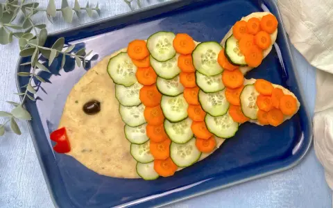 Un simpatico pesce finto ricetta, con corpo di purè, scaglie di cetriolo e carota, occhio d'oliva e bocca di peperone rosso.