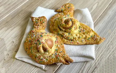 Due cuddure cu l'ova, dolci pasquali decorati con zuccherini colorati, riposano su un panno bianco.
