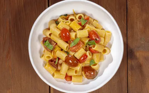Un piatto invitante di pasta con pomodorini freschi, basilico e un filo d'olio.
