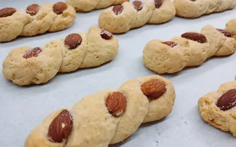 Intorchiate pugliesi ricetta originale: biscotti intrecciati dorati con mandorle e zucchero, pronti per essere gustati.