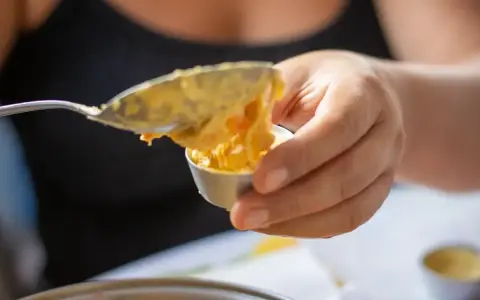 Una mano versa un cucchiaio di budino di riso in una coppetta.