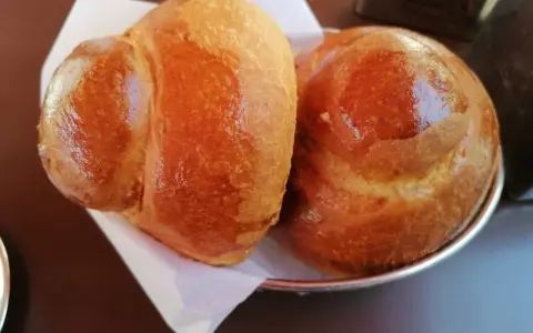 Due brioche col tuppo dorate e lucide, pronte per essere gustate con una granita.