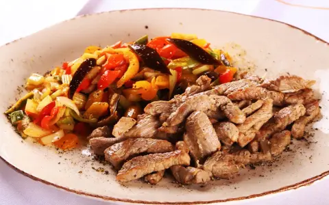 Straccetti di vitello succulenti serviti con un contorno colorato di verdure saltate, un piatto invitante e saporito.