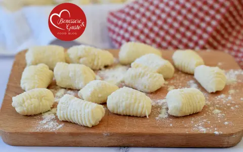 Gnocchi di ricotta freschi, pronti per essere cucinati, spolverati di farina su un tagliere di legno.