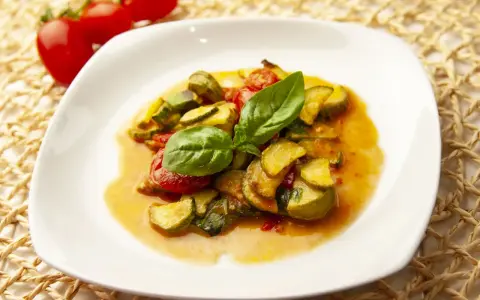 Zucchine in umido con pomodorini e basilico fresco, un piatto estivo profumato e saporito.