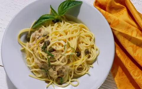Spaghetti al tonno con capperi, scorza di limone e basilico, un piatto gustoso e profumato.