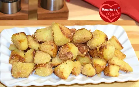 Patate sabbiose in padella, dorate e croccanti, servite su un piatto bianco. Un contorno irresistibile.