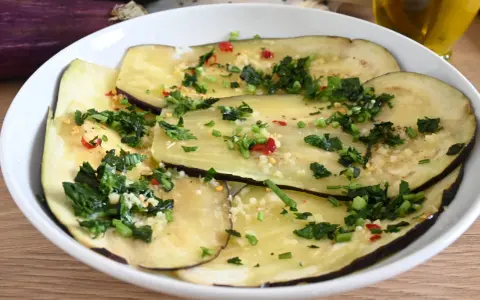 Fette di melanzane marinate crude, condite con aglio, prezzemolo e peperoncino.
