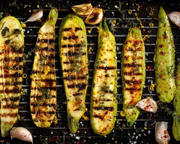 Zucchine grigliate perfette, condite con erbe aromatiche, aglio e scorza di limone, pronte per essere gustate.