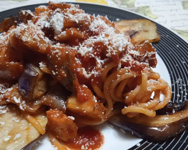 Un piatto invitante di pasta alla norma con melanzane fritte, sugo di pomodoro e ricotta salata grattugiata.