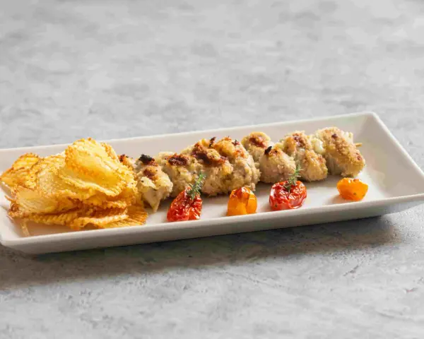 Involtini alla messinese su uno spiedino, accompagnati da patatine croccanti e pomodorini confit.