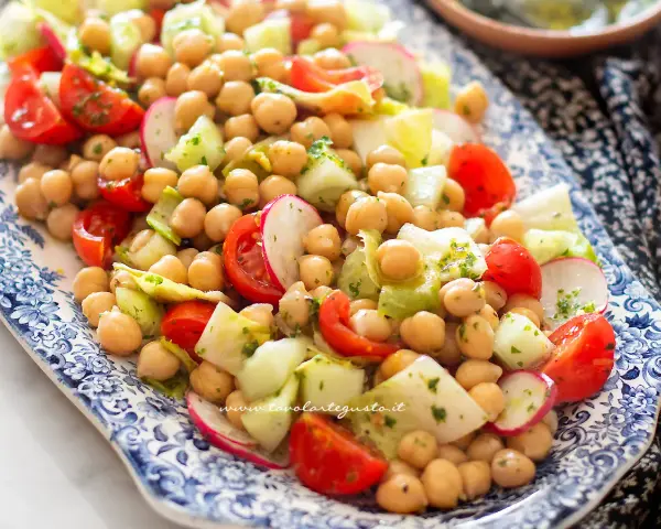 Deliziosa insalata di ceci fredda con pomodorini, cetrioli e ravanelli, condita con erbe fresche. Perfetta per un pasto leggero e gustoso.