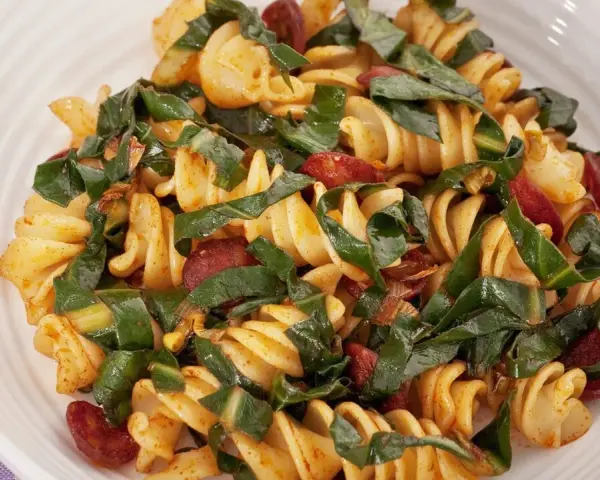 Fusilli conditi con bietole, salsiccia e un tocco di spezie. Un piatto saporito e colorato.