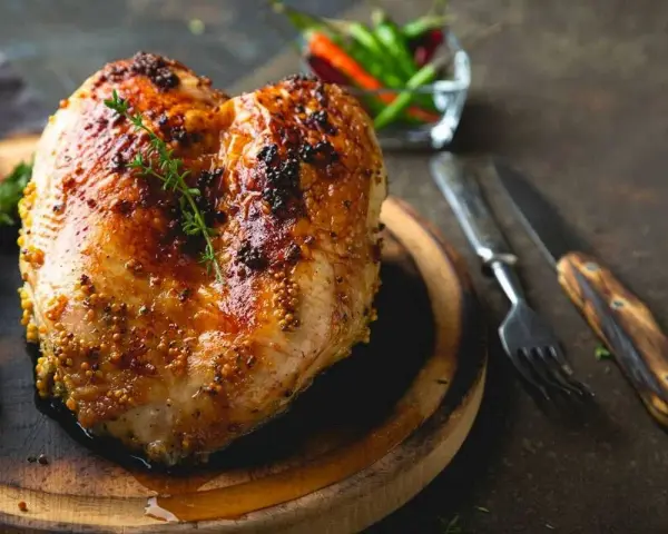 Succulento petto di pollo al forno, dorato e speziato, pronto per essere gustato con erbe aromatiche e peperoncini.