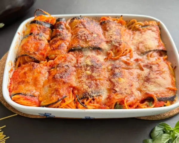 Involtini di melanzane con spaghetti al forno, ricoperti di sugo e formaggio filante, pronti per essere gustati.