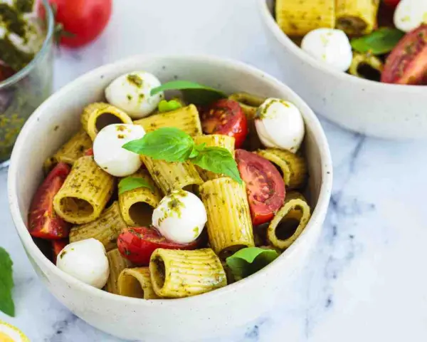 Un piatto di pasta pesto e pomodorini, con mozzarelline e basilico fresco. Un'esplosione di sapori mediterranei.