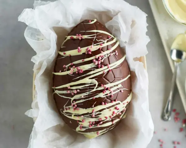 Un magnifico uovo di Pasqua fatto in casa, decorato con cioccolato bianco e granella rosa.